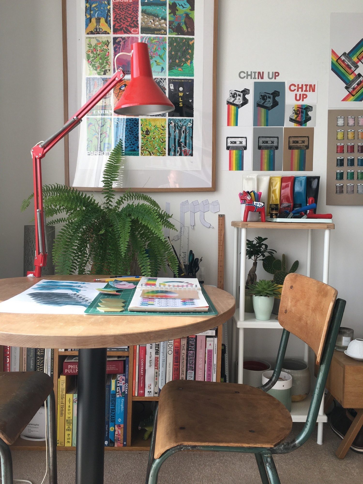 Dave Hall's printing studio, round desk with a chair, lamp, printing supplies and lino prints on the wall